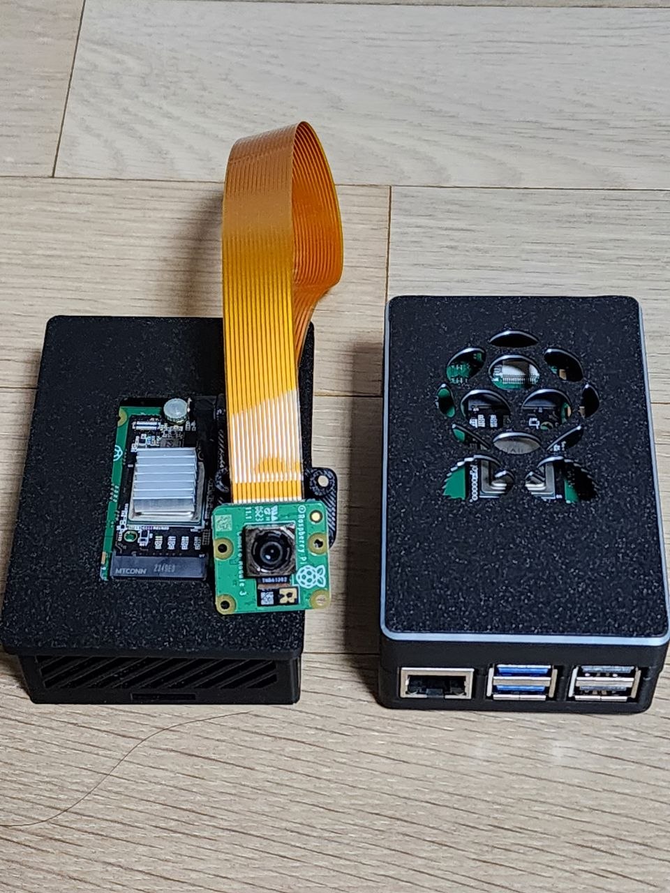 카메라가 연결된 Raspberry Pi 5 AI Kit 구성과 일반 Raspberry Pi 5 케이스 비교